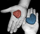 One red and one blue rock in two children's hands