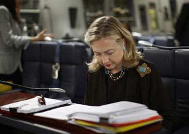 Clinton sighing at a desk