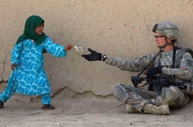 Middleeastern child handing a US soldier a gift