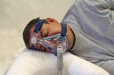 Man wearing sleep apnea mask in bed