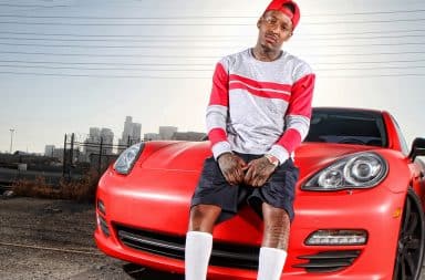 Rapper sitting on a fancy red Porsche car