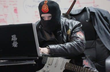 Ninja holding a guitar at a laptop computer