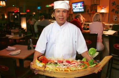 Japanese chef holding a wooden sushi boat