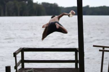 Teenage boy jumps into ocean from a dock