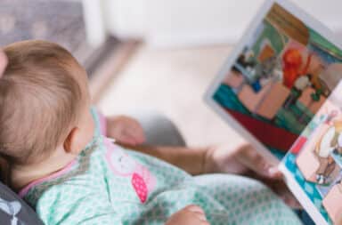 Baby reading book in bed