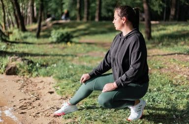 Woman by the water squatting down smarmily